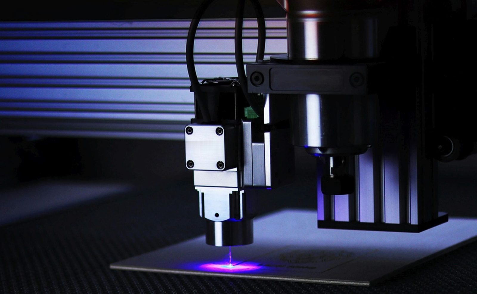 Close-up of a laser head engraving a pattern on a flat panel